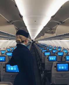 a woman standing on an airplane looking out the window at rows of computer monitors and televisions