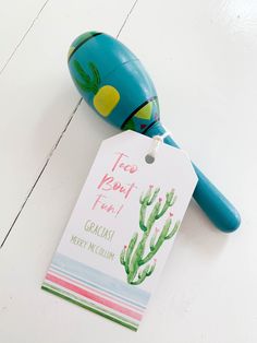 a toy with a tag attached to it sitting on a white floor next to a cactus