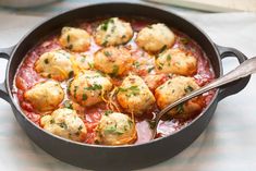 a pan filled with meatballs and sauce on top of a table