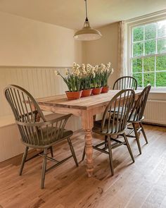 a dining room table with four chairs and a potted plant on the table in front of it