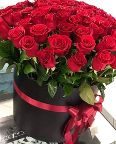 a large bouquet of red roses in a black box with a bow on the side