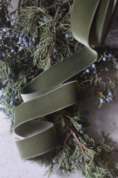 olive green ribbon with blue flowers and greenery next to it on a marble surface