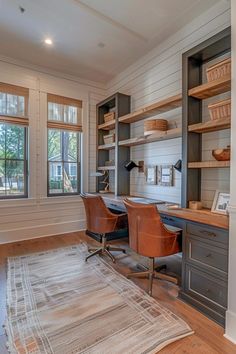 a home office with two desks and open shelving units on the wall, along with an area rug