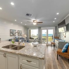 a kitchen with white cabinets and granite counter tops next to a living room area that has sliding glass doors