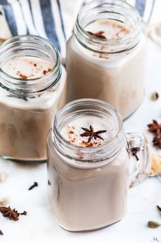 three mason jars filled with hot chocolate and cinnamon on top of a white tablecloth