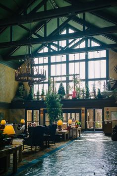 an indoor swimming pool in a large building with lots of windows and plants on the wall