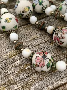 Hand painted porcelain white beads beautifully & intricately painted with pink & soft lilac blue magnolia flowers, interspersed with smaller white beads & stunning brass pergola  beads.A vintage Chinese stunner. Artisan White Single Strand Beads, Artisan Hand Painted White Necklace, Artisan Hand Painted White Necklaces, Artisan White Hand Painted Necklaces, Vintage Hand Painted White Jewelry, Vintage White Hand Painted Jewelry, White Hand Painted Round Necklace, Bohemian White Hand Painted Necklace, White Hand Painted Round Necklaces