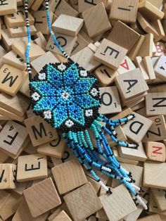 a blue beaded necklace sitting on top of scrabble letters