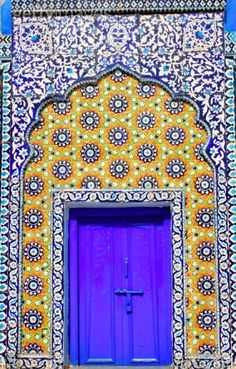 an ornate building with a purple door and cross on the front entrance, in morocco