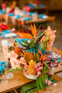 an arrangement of colorful flowers in a vase on a table at a wedding or party