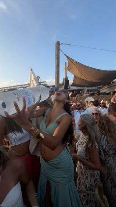 a group of people standing next to each other at a party with one woman drinking from a water bottle