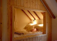 an attic bedroom with white bedding and wooden beams on the walls, along with two lamps