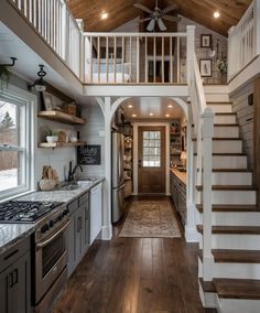 a kitchen and stairs in a home with wood flooring, white walls and ceiling