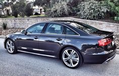 an audi car parked on the side of the road in front of a brick wall