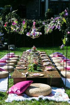 a long table is set up with flowers and plates on it for an outdoor party