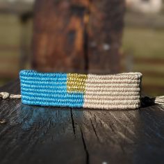 a blue and white striped bracelet sitting on top of a wooden table next to a fence