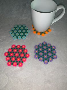 three coasters with different colors and designs on the floor next to a coffee cup