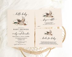 three baby shower cards sitting on top of a white blanket next to a wicker basket