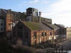 an old brick building with lots of windows and graffiti on the side of it's roof