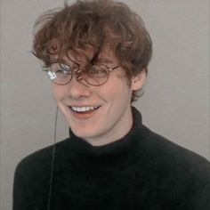 a young man wearing glasses is smiling for the camera with headphones in his ears