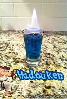 a shot glass with blue liquid in it sitting on a counter next to the word hadokuen