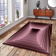 a living room with wooden floors and large rugs on the floor in front of windows