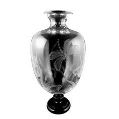 a black and white photo of a vase with a butterfly on the bottom, in front of a white background