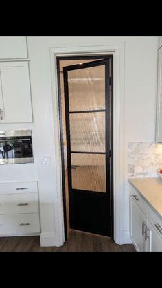 a kitchen with white cabinets and black door