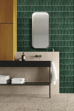 a bathroom with green tiled walls and flooring next to a wooden cabinet, mirror and sink