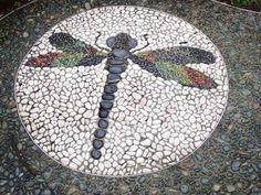 a dragonfly is made out of pebbles on a circular table with stones