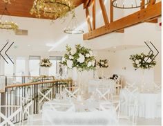 tables and chairs are set up for a wedding reception with white flowers in vases hanging from the ceiling