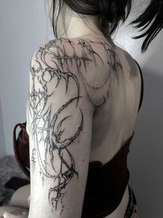 the back of a woman's shoulder with tattoos on her left arm and chest