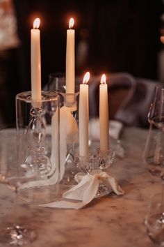 candles are lit on a table with wine glasses