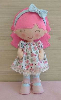 a little doll with pink hair and blue shoes is standing on a pink tablecloth