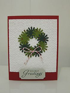 a christmas card with a green wreath on it and the words holiday greetings written in white