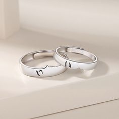 two wedding rings sitting on top of a white counter next to each other with faces drawn on them