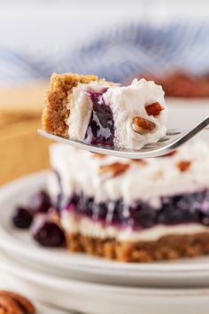 a piece of cheesecake with blueberries and whipped cream on top is being held by a fork