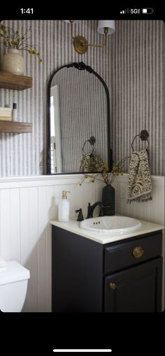 a bathroom sink with a mirror above it and a toilet in the corner next to it