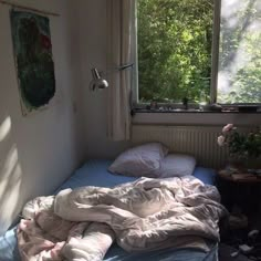 an unmade bed sitting next to a window