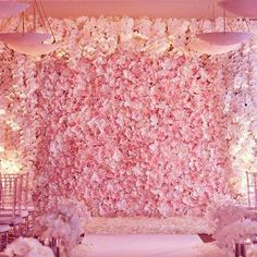 a wedding ceremony setup with pink and white flowers on the wall