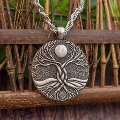 a necklace with a tree and moon design on the front, sitting on a wooden surface