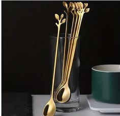 three golden spoons and two cups on a table