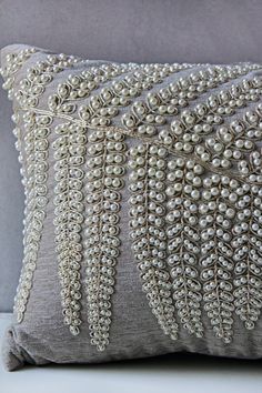 a gray pillow with beading on it