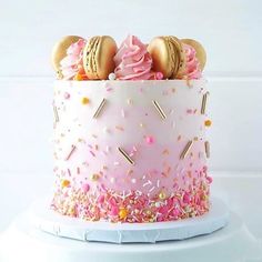 a pink cake with sprinkles and macaroons on top