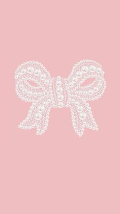 a white bow with pearls on it against a pink background, in the shape of an ornament