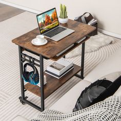 a laptop computer sitting on top of a wooden table next to a white rug and pillows