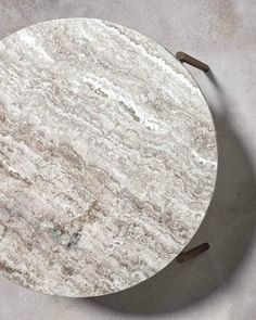 a round marble table with metal legs on a gray surface, top view from above