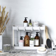 a bathroom counter with soaps, lotions and other items on it in front of a white tiled wall