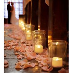 candles are lined up on the floor with petals