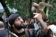 a man holding an owl up to the sky